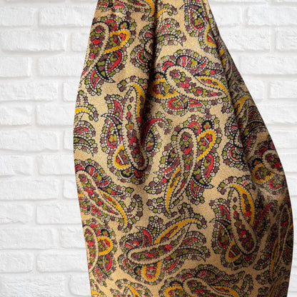 Patterned fabric with colorful paisley design on a white brick wall background