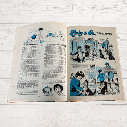 Open book with comic strip titled 'Lucky & Co. Detectives' on a wooden surface