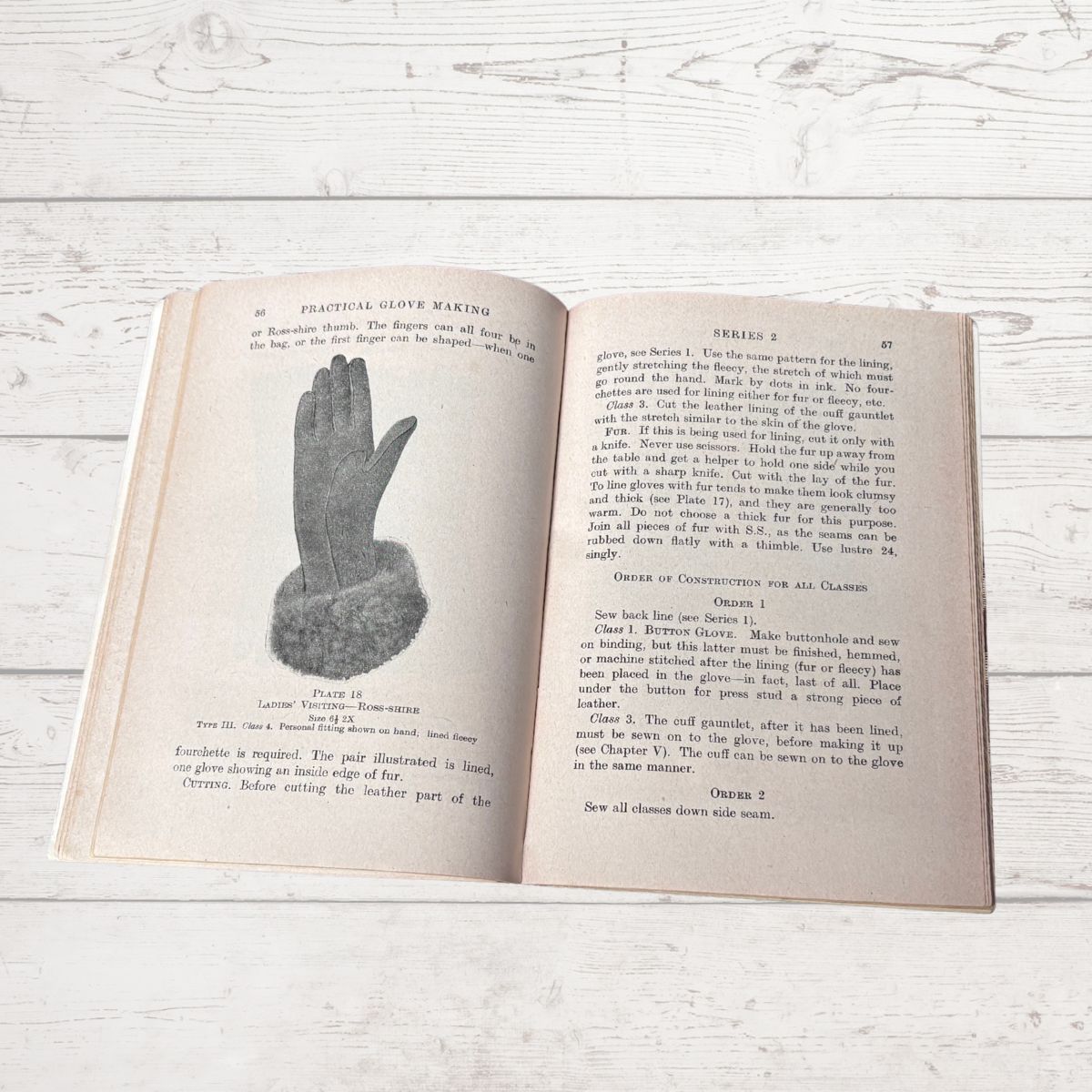 Open book with text and illustration of a hand on a wooden surface