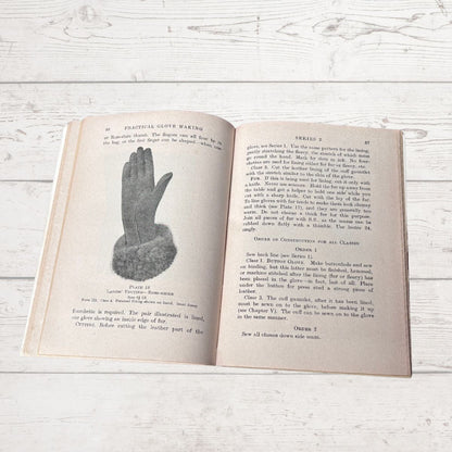 Open book with text and illustration of a hand on a wooden surface