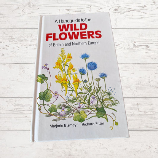 Book titled 'A Handguide to the Wild Flowers of Britain and Northern Europe' on a wooden surface
