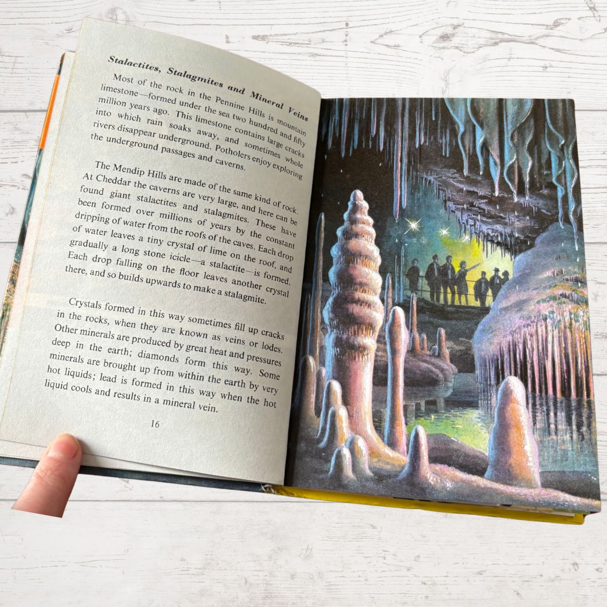 Open book showing a page with text and a colorful illustration of a cave scene.