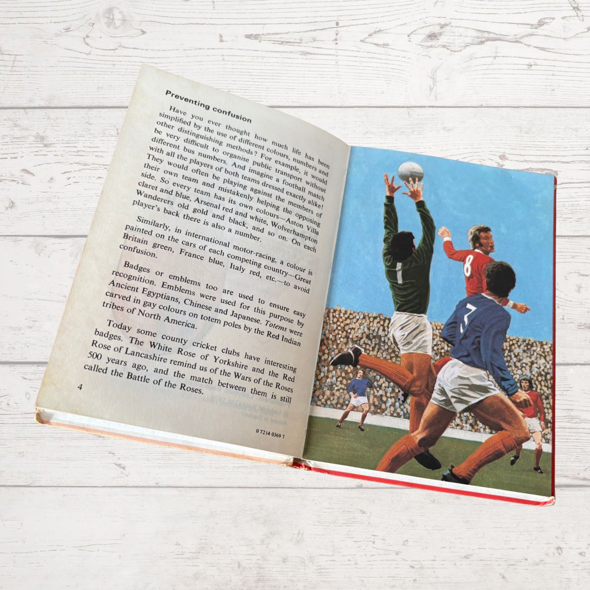 Open book showing a page with a vintage illustration of a sports scene on a wooden surface.