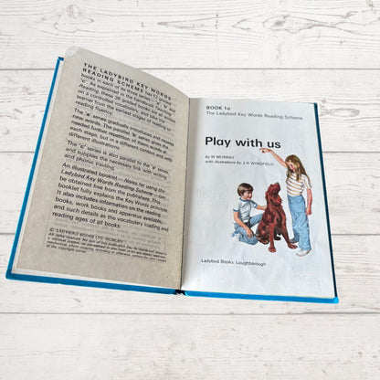 Open book with text and illustration of children playing with a dog on a wooden surface
