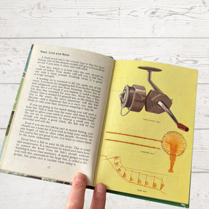 Open book with fishing illustrations and text on a wooden surface