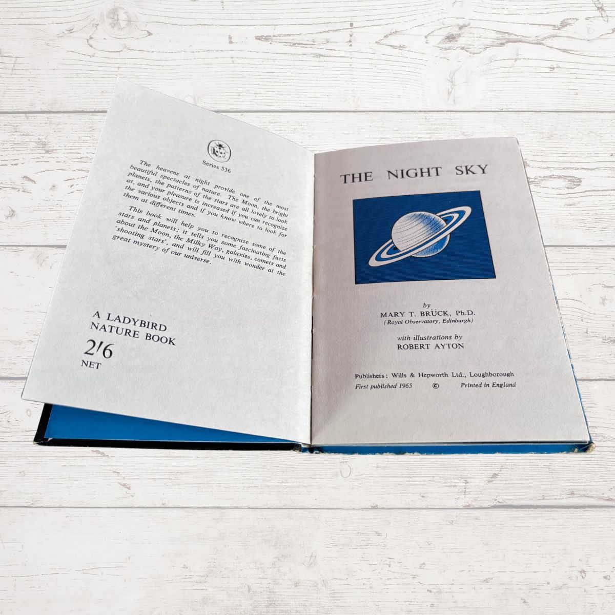 An open hardcover book titled 'The Night Sky' by Mary T. Bruck, showing the title page and introductory text on the left and right pages, placed on a white wood surface.