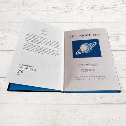 An open hardcover book titled 'The Night Sky' by Mary T. Bruck, showing the title page and introductory text on the left and right pages, placed on a white wood surface.