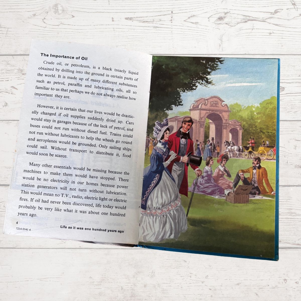 An open children's book spread showing a page about the importance of oil, with a large historical illustration on the right. The book is photographed on a light whitewashed wood surface.