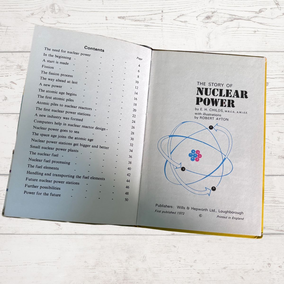 An open book showing the 'Contents' page on the left and the title page for 'The Story of Nuclear Power' on the right, photographed on a light wood surface.