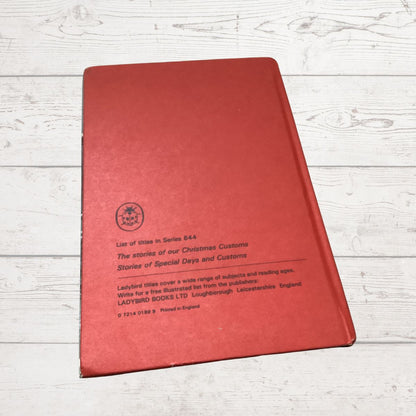 A red hardcover book titled 'List of titles in Series  644 Ladybird Books Ltd, photographed from an angle on a white wood plank background.