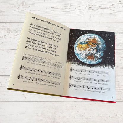 Open book with lyrics and a world illustration on a white wooden surface