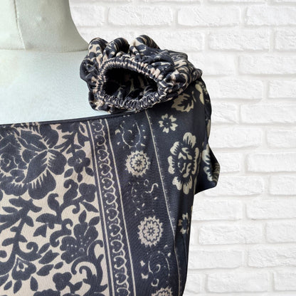 Black and white patterned fabric draped over a mannequin against a white brick wall.