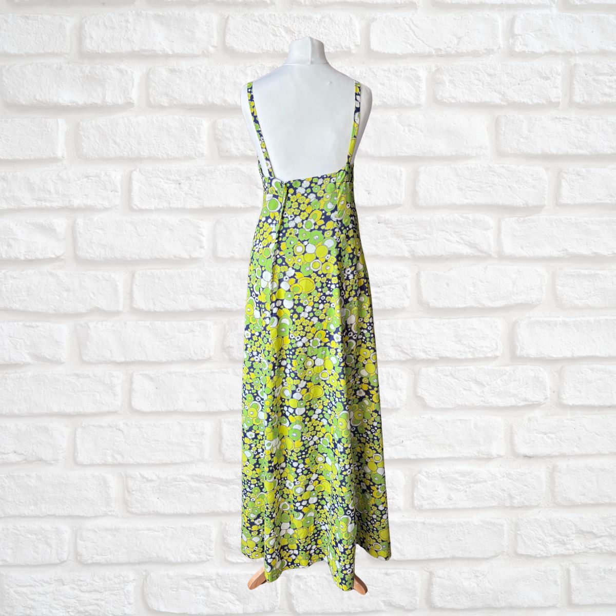 Floral dress on a mannequin against a white brick wall background