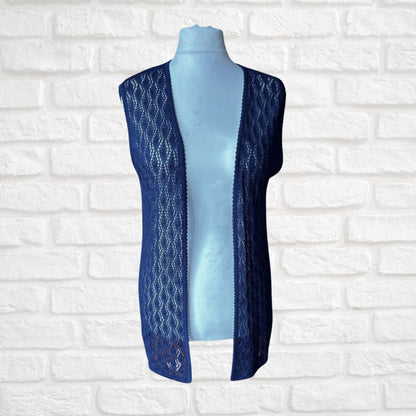 A sleeveless open-front lace vest in dark blue, displayed on a light blue mannequin torso against a white brick wall background.