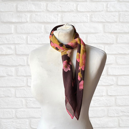 Colorful floral scarf on a mannequin against a white brick wall background