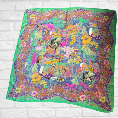 Colorful scarf with a floral and nature-themed design on a white brick background