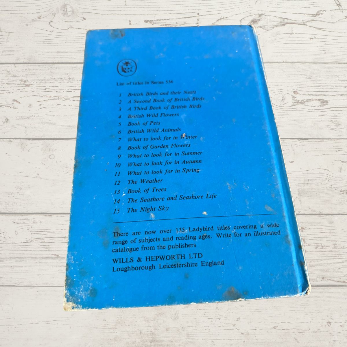A vintage blue book cover or catalogue page with printed text listing British birds, photographed on a white painted wood surface. The visible publisher text at the bottom reads 'WILLS & HEPWORTH LTD'.