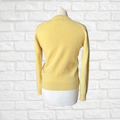 Yellow sweater on a mannequin against a white brick wall background