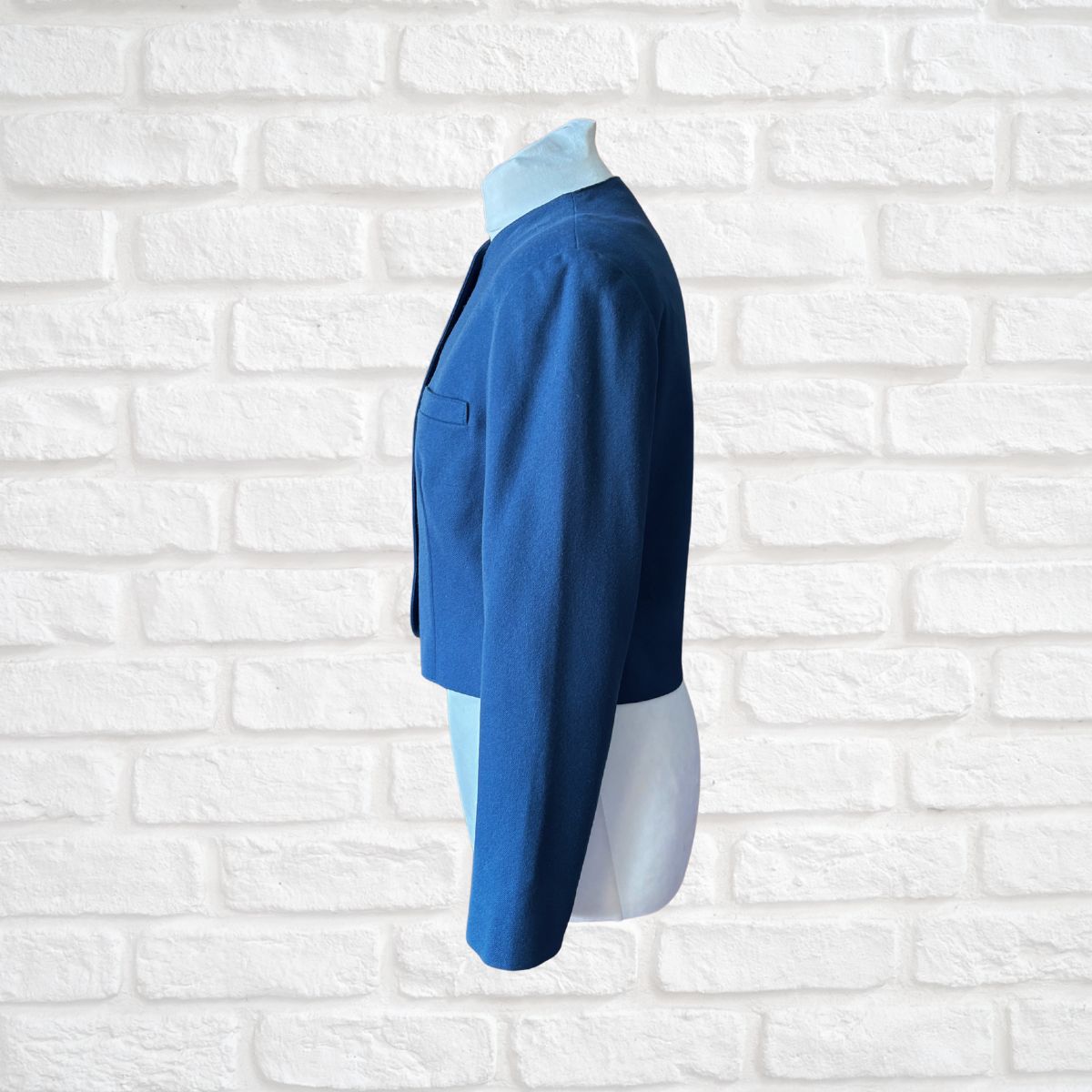Blue jacket on a mannequin against a white brick wall background
