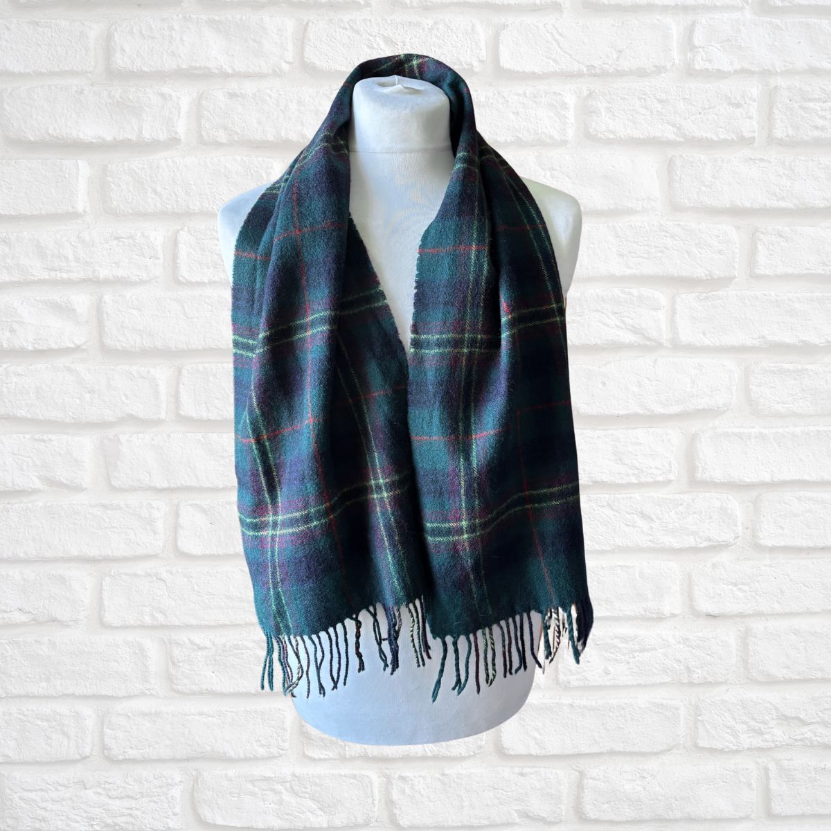 Plaid scarf on a mannequin against a white brick wall background