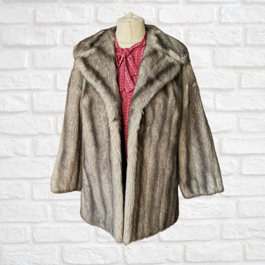 Grey fur coat on a mannequin against a white brick wall background