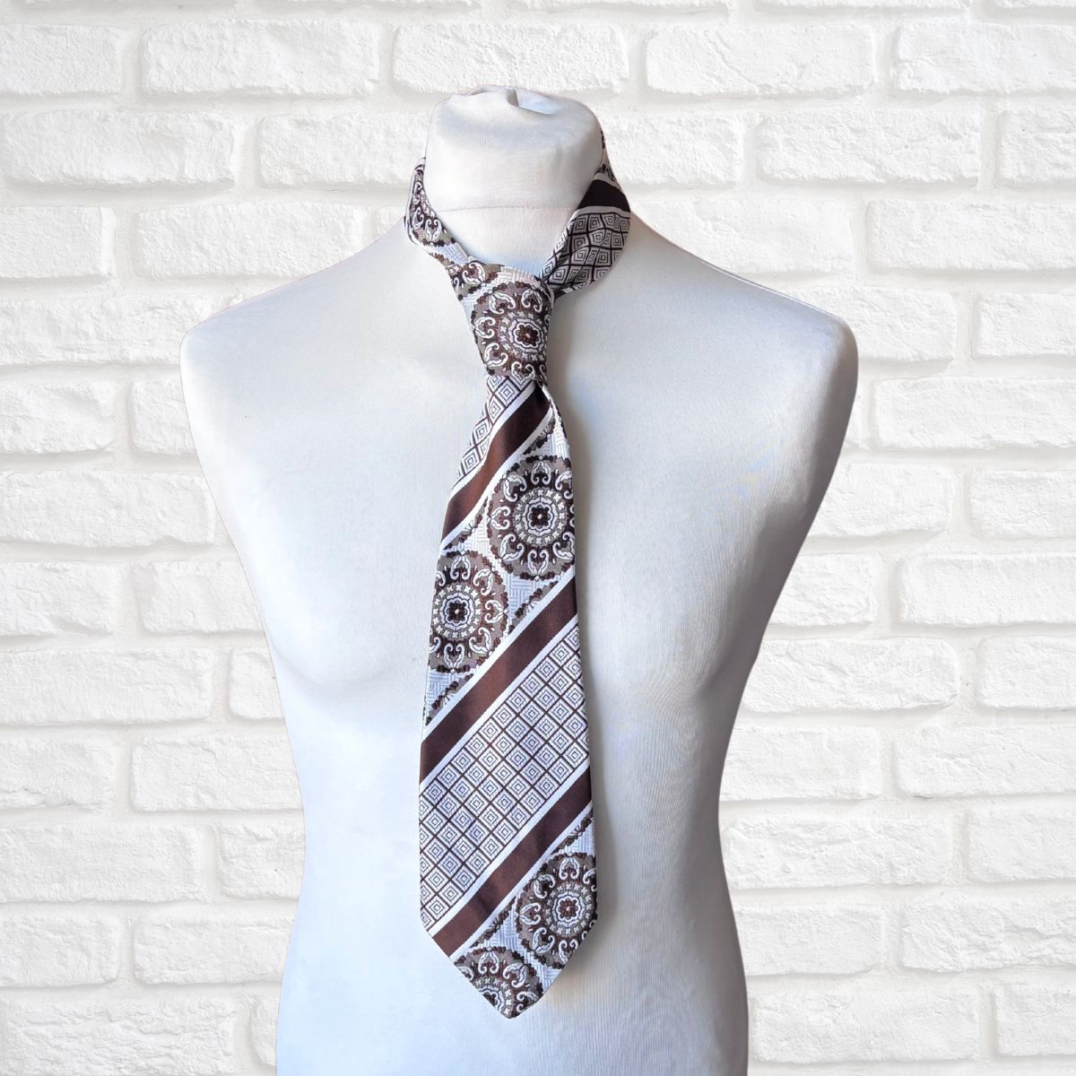 Patterned necktie on a mannequin against a white brick wall background