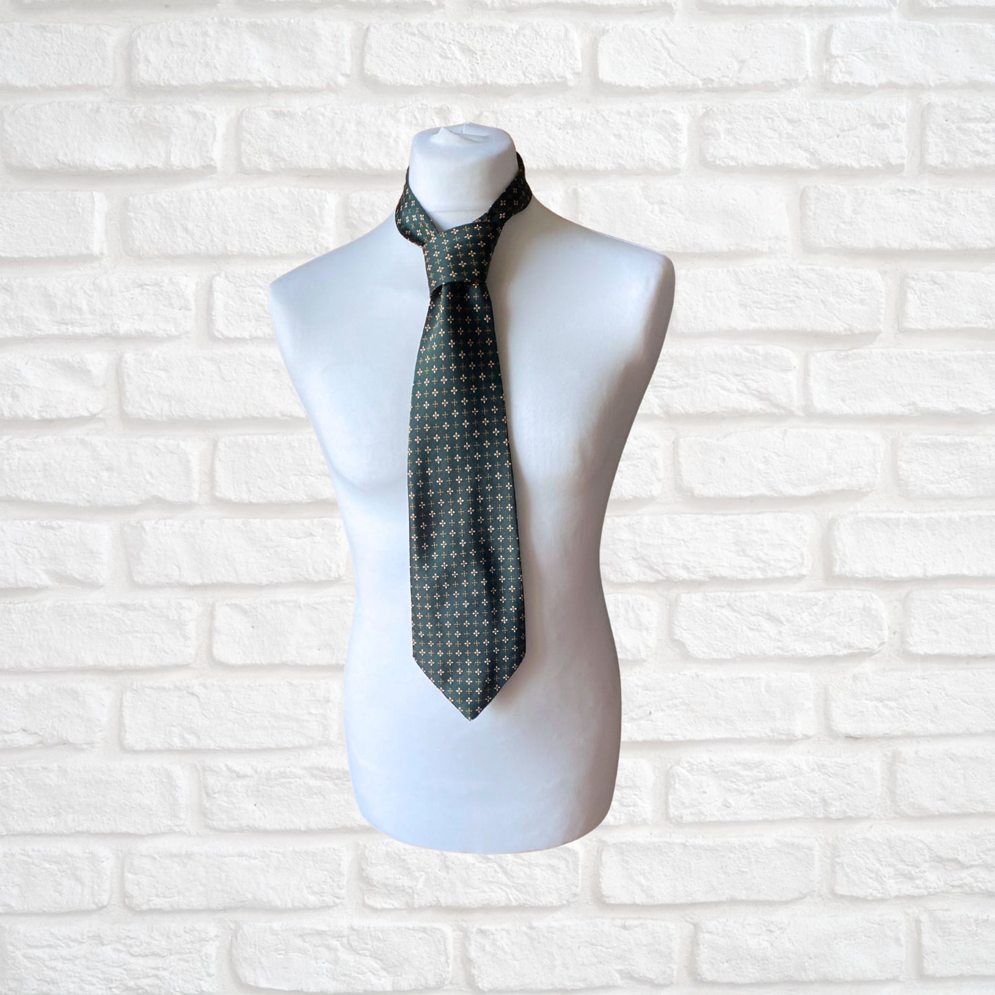 A green, orange and white geometric floral  print vintage 70s tie on a mannequin.