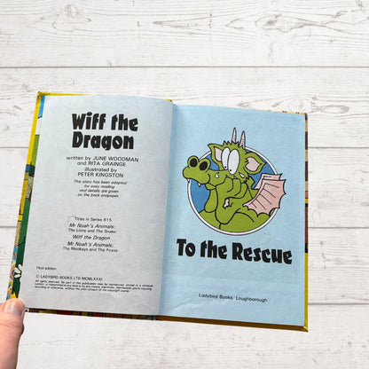 Open book titled 'Wiff the Dragon To the Rescue' with a dragon illustration on a wooden surface.