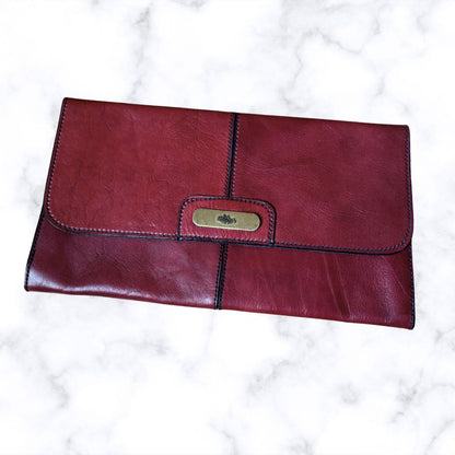 Red leather clutch bag with gold clasp on a white marble background