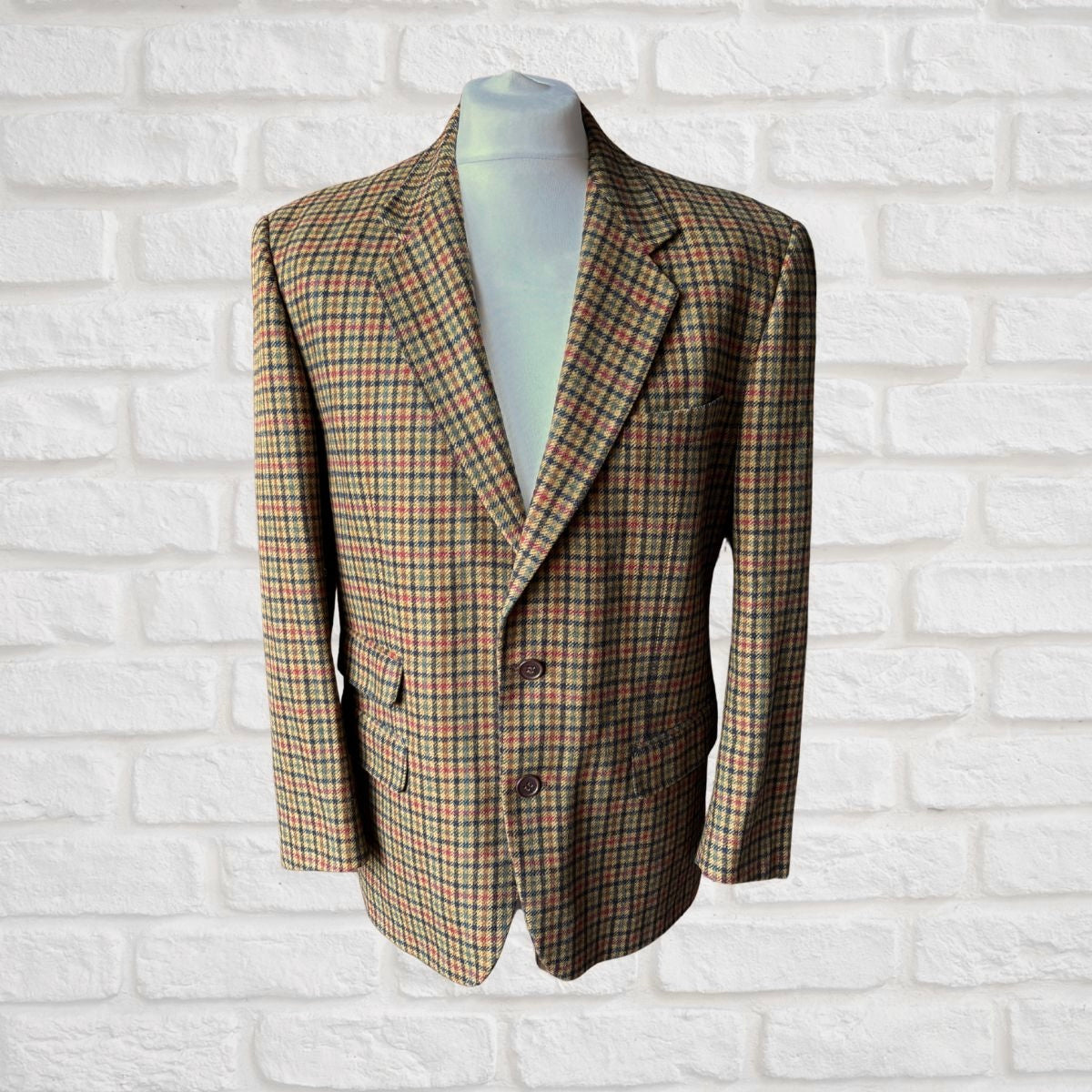 Checked blazer on a mannequin against a white brick wall