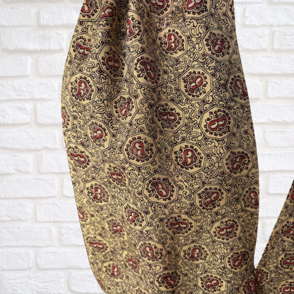 Patterned cravat with red and yellow  design on a white brick wall background