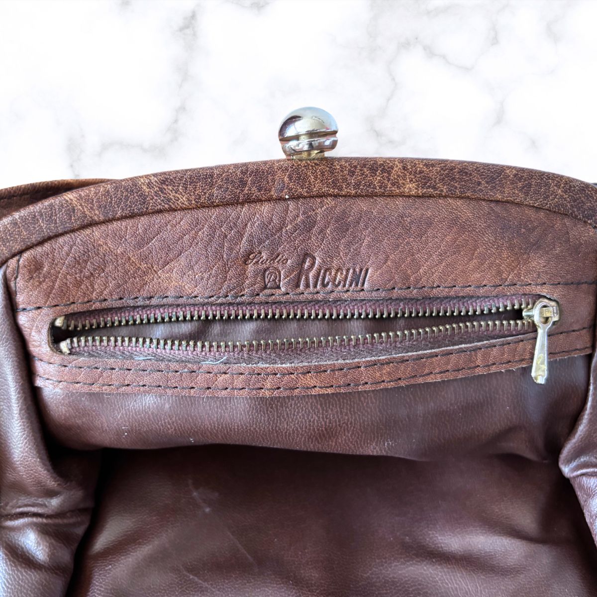 Close-up of a brown bag interior with a visible brand logo on a white background