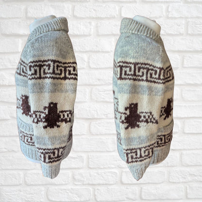 Pair of knitted eagle sweaters with a pattern on a white brick background