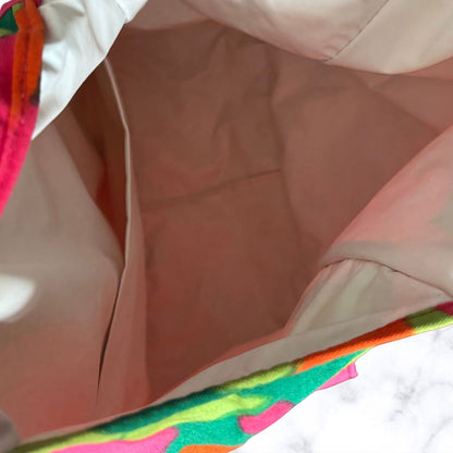 Close-up view inside a soft fabric bag or pouch, showing a plastic interior lining with a colourful patterned trim visible along the edges.