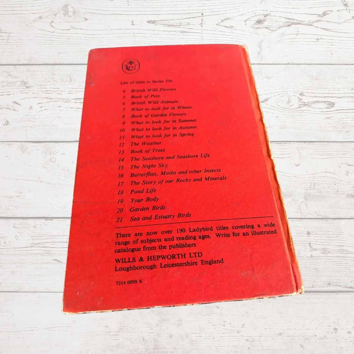 A vintage red book cover photographed on a white-washed wooden surface.