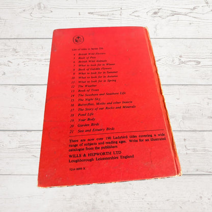 A vintage red book cover photographed on a white-washed wooden surface.