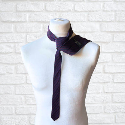 Mannequin wearing a navy and red tie against a white brick wall background