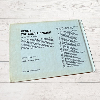 Back cover of a book titled 'Percy the Small Engine' with text on a light wooden surface.